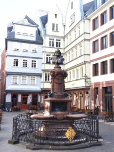 Nachmittagsstimmung auf dem Hühnermarkt in der rekonstruierten Frankfurter Altstadt mit Friedrich-Stoltze-Brunnen von 1895. Hier ungefähr begann der Spaziergang, den Friedrich Stoltze 1821 als 5Jähriger mit seinem Großvater machte und später in seiner Erzählung „Von Frankfurts Macht und Größe“ beschrieb. © Rudolf Dederer